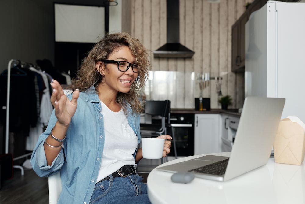 A career coach holds coffee while on a video call