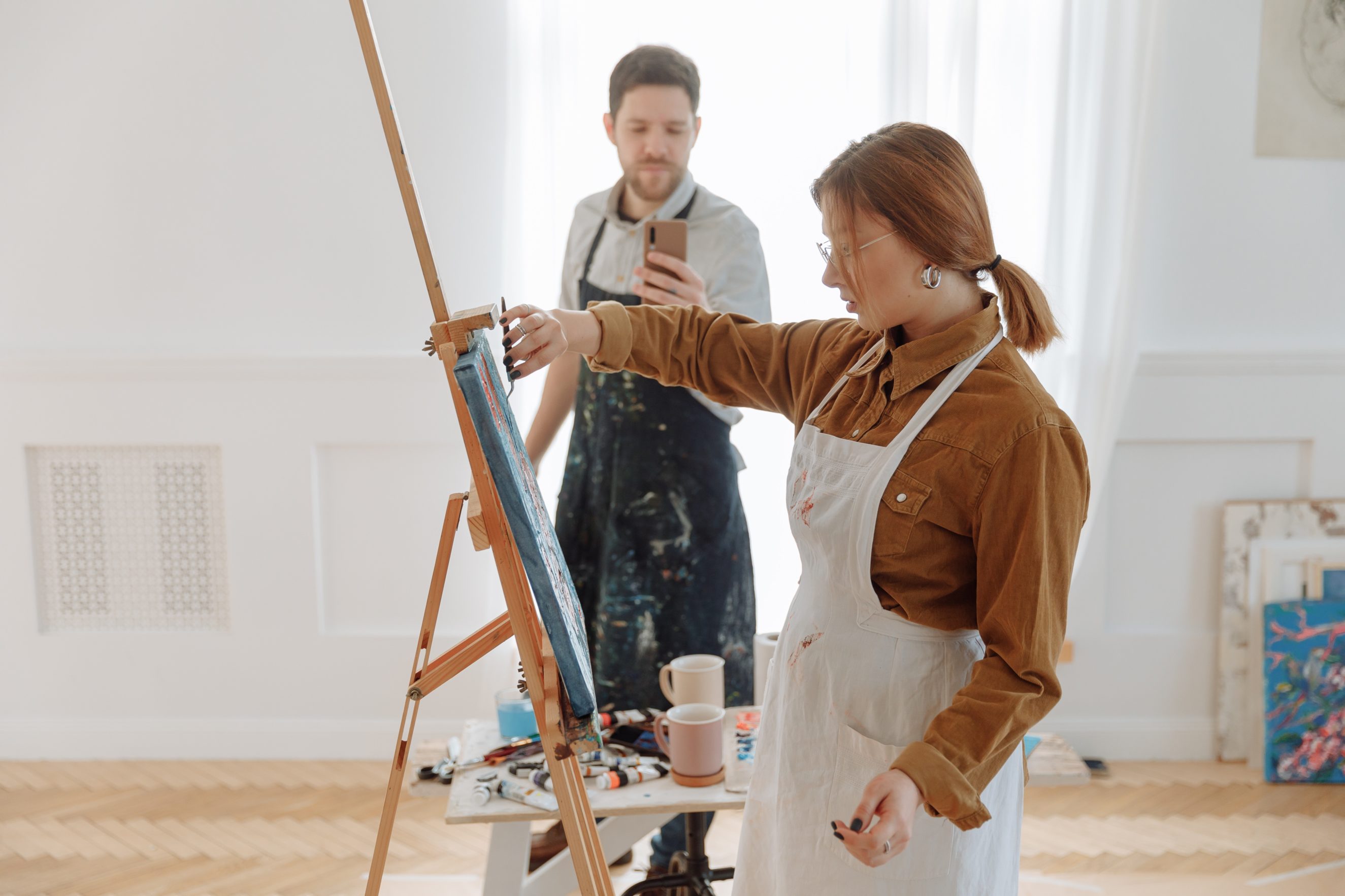 man filming woman painting